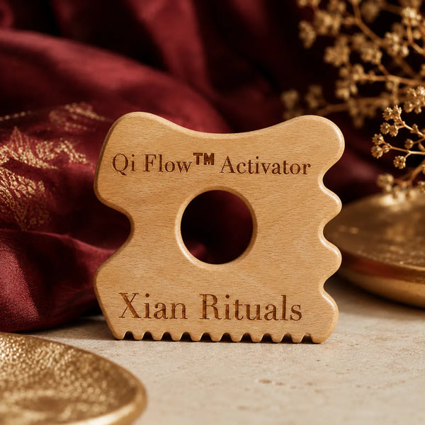 Qi Flow™ Activator wooden gua sha tool on burgundy background for face and body self-care